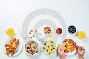 Breakfast table setting with flakes, juice, croissants, pancakes