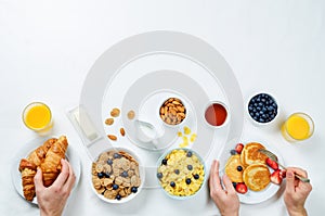 Breakfast table setting with flakes, juice, croissants, pancakes