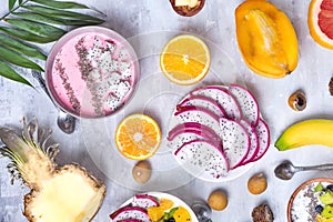 Breakfast table with yogurt strawberry smoothie bowls and fresh tropic fruits on a gray stone background. Acai bowl of