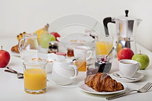 Breakfast time. Croissants and orange juice, jam and honey. Coffee with cream or milk. Fruits - bananas, red and green apples.