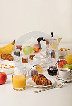 Breakfast time. Croissants and orange juice, jam and honey. Coffee with cream or milk. Fruits - bananas, red and green apples. Ri