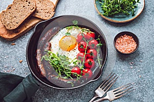 Breakfast time, fried egg with sausages and cherry tomatoes