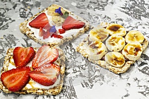 Breakfast with toaster and oat bread, buttered with butter, jam, strawberries and bananas on a concrete table.