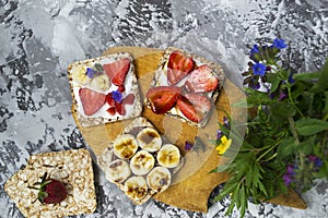 Breakfast with toaster and oat bread, buttered with butter, jam, strawberries and bananas on a concrete table.