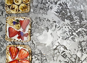 Breakfast with toaster and oat bread, buttered with butter, jam, strawberries and bananas on a concrete table