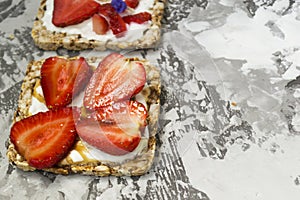 Breakfast with toaster and oat bread, buttered with butter, jam, strawberries and bananas on a concrete table