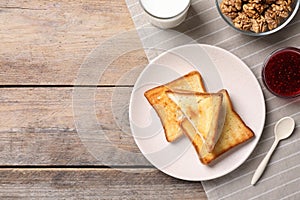 Breakfast with toasts, jam and glass of milk on wooden table, flat lay. Space for text