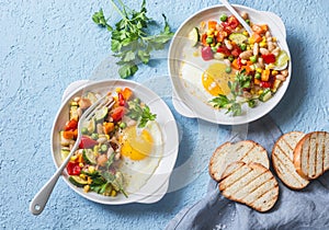 Breakfast vegetable hash with fried eggs on a blue background, top view. Healthy food