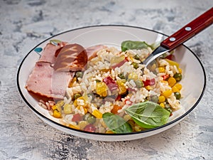 Breakfast with vegetables and rice with slices of ham on a light plate