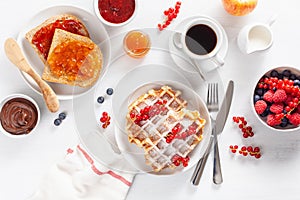 Breakfast with waffle, toast, berry, jam, chocolate spread and c