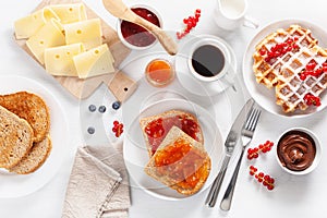 Breakfast with waffle, toast, berry, jam, chocolate spread and c