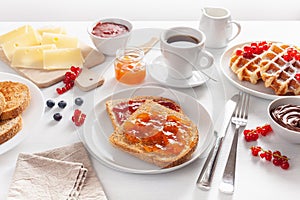 Breakfast with waffle, toast, berry, jam and coffee