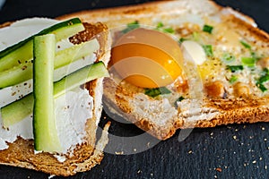 Breakfast of warmed toast, egg, cheese, green onions and cucumber. Beautiful serving of toast for breakfast. Selected