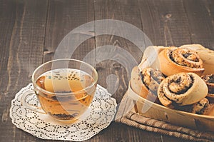 Breakfast whith rolls with poppy and glass cup whith tea/Breakfast whith rolls with poppy and glass cup whith tea on a dark wooden