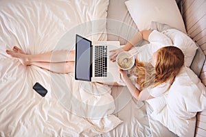 Breakfast and wifi, what I love. Shot of a young woman eating breakfast and using a laptop at home.