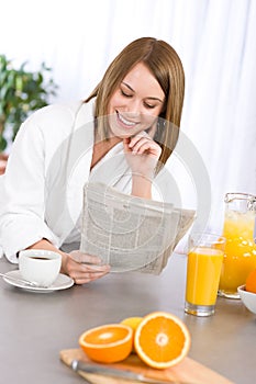 Breakfast - woman reading newspaper in kitchen