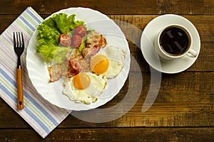 Breakfast on a wooden table. Coffee fried egg with bacon.