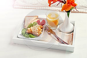 Breakfast on a wooden tray eggs scrambled and juice