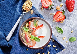 Breakfast with yogurt, granola of muesli and strawberries on gray concrete table background