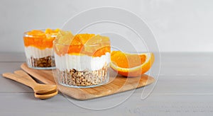 Breakfast of yogurt, jam, orange and granola on a gray wooden table. Healthy food. Dessert. Banner with copy space