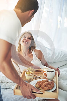 Breakfast for you, baby. a loving young couple enjoying breakfast in bed.