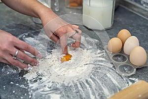 breaking eggs with women& x27;s hands into flour to make dough for cakes.