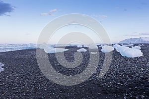 Breaking Ice from glacier on small black rock sand beach, Iceland
