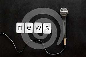 Breaking news concept. Microphone on black background top-down