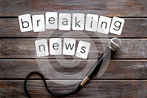 Breaking news concept. Microphone on dark wooden background top-down