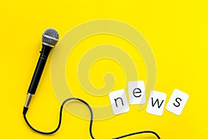 Breaking news concept. Microphone on yellow background top-down copy space