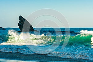 Breaking ocean wave falling down at sunrise time