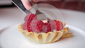 Breaking a raspberry cake with a dessert fork and knife