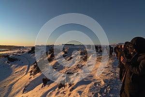 The breaking of the tectonic plates of the Gulfoss waterfall illuminated by the first rays of the dawn sun. Tourists watching and