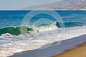 Breaking wave on ocean, with backwash on open ocean with horizon, sandy beach