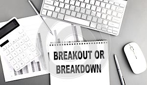 BREAKOUT OR BREAKDOWN text on notebook with keyboard and chart