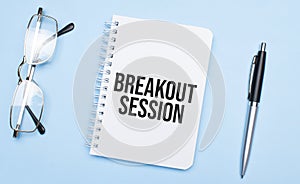 breakout session words in white notepad, pen and glasses on blue background. Concept