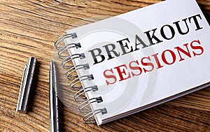 BREAKOUT SESSIONS text on notebook with pen on wooden background