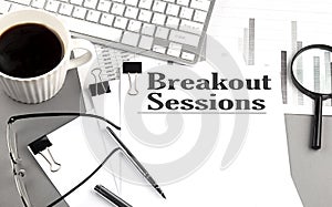 BREAKOUT SESSIONS text on a paper with magnifier, coffee and keyboard on grey background