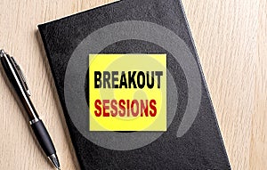 BREAKOUT SESSIONS text on a sticky on black notebook with pen