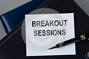 BREAKOUT SESSIONS - words on white sheet on a black leather book with pen