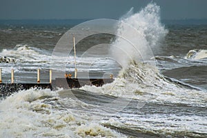 Breakwater and harbour in stormy weather with huge waves crashing over the walls pier. Abnormally strong storms in the middle