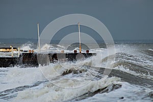 Breakwater and harbour in stormy weather with huge waves crashing over the walls pier. Abnormally strong storms in the middle