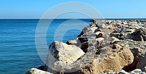 Breakwater of large stones in blue sea to horizon, road to sea, beautiful seascape, Mediterranean beaches