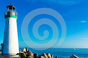 Breakwater lighthouse stands on jetty at California Pacific Ocean coast under blue sky at the daytime