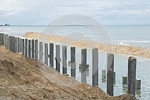 Breakwater Seawall wave impact barrier construction at sea shore sand bay area in process of installing concrete pillars