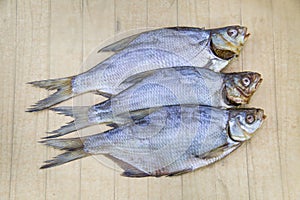 Bream Latin Abramis brama dried with the head folded in a row on a wooden table. Food is a delicacy snack