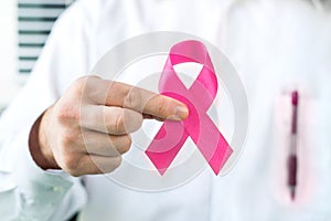 Breast cancer awareness concept. Doctor holding pink ribbon.