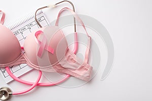 Breast cancer awareness concept. Top view photo of pink brassiere with pink ribbon stethoscope and calendar on isolated white