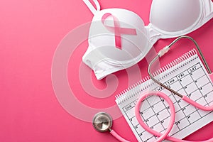 Breast cancer awareness concept. Top view photo of pink ribbon attached to white brassiere calendar and stethoscope on isolated