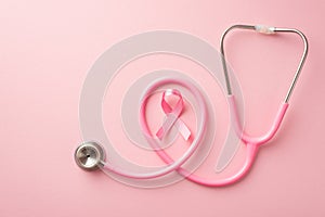 Breast cancer awareness concept. Top view photo of pink silk ribbon and stethoscope on isolated pastel pink background